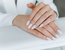 Conceito de cuidado com as unhas. Foto em close-up de uma linda mulher mãos mostrando unhas perfeitas, pintada com esmalte nude em um salão de unhas