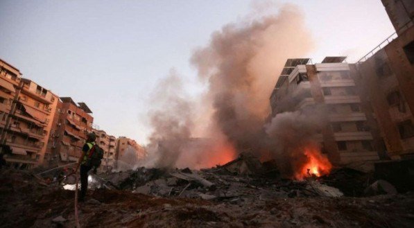 Socorrista combate incêndio em meio a ruínas fumegantes de um dos seis prédios atingidos no bairro xiita de Haret Hreik, no sul de Beirute