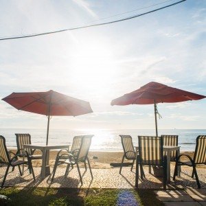 Imagem de um ponto de descanso de um hotel com mesas e cadeiras na praia