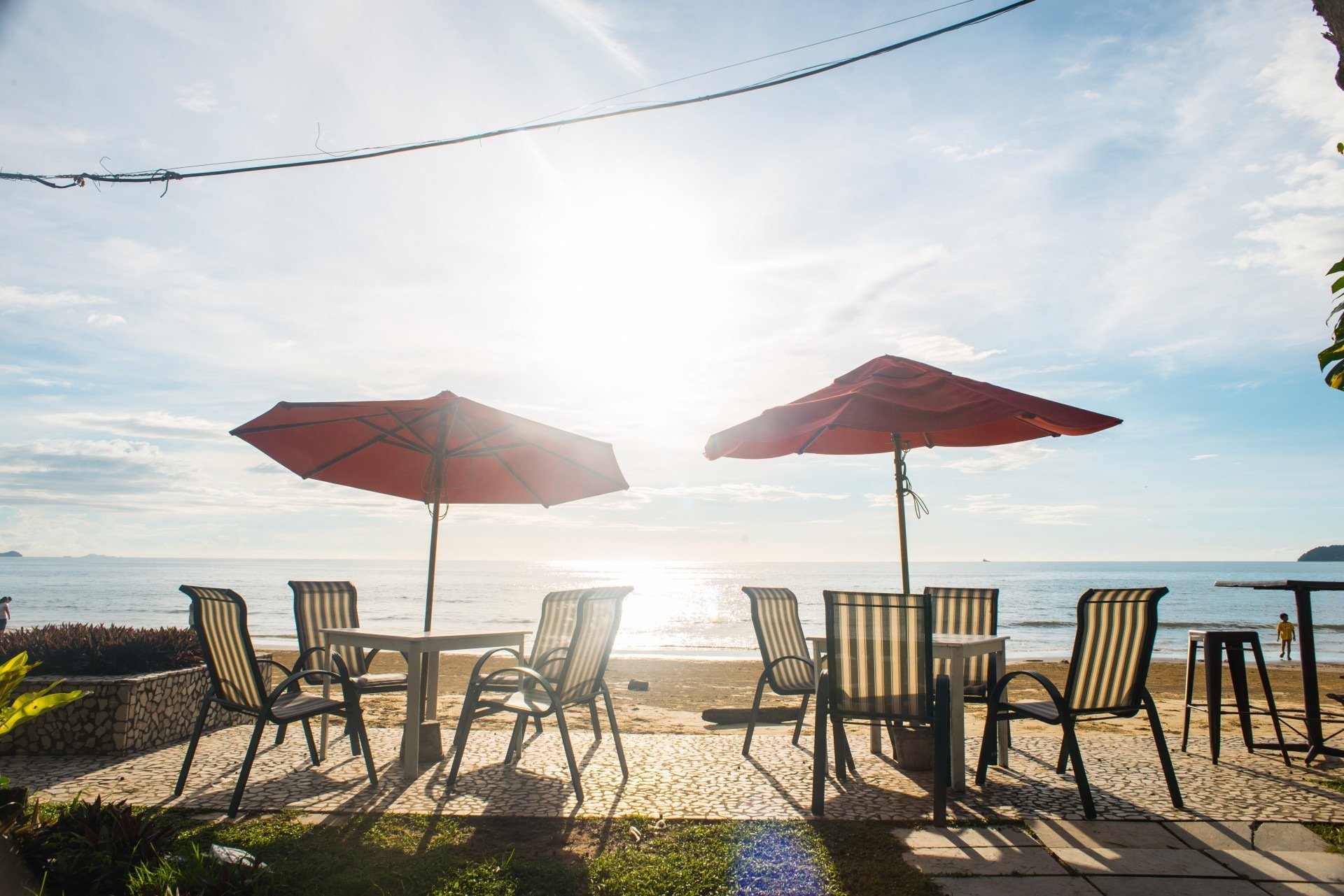 Imagem de um ponto de descanso de um hotel com mesas e cadeiras na praia