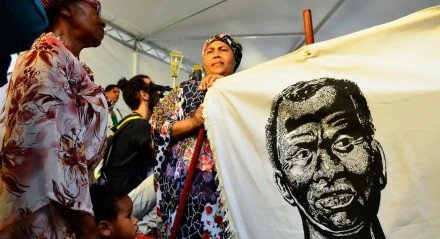 Imagem de mulheres negras segurando um bandeira com o rosto de Zumbi dos Palmares