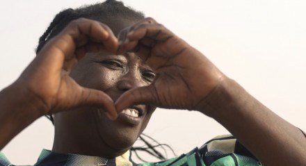 Imagem de uma mulher negra fazendo um coração com as mãos