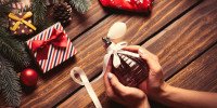 Mãos femininas segurando perfume como presente de Natal.