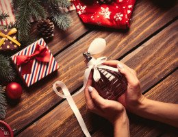 Mãos femininas segurando perfume como presente de Natal.