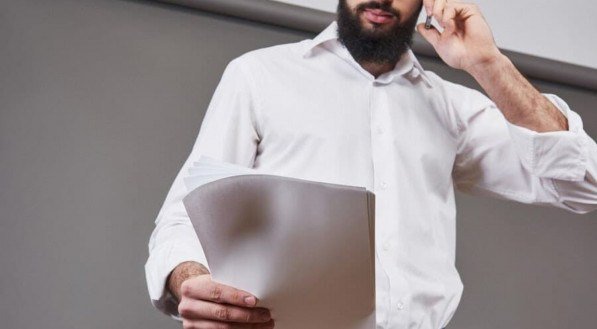 Imagem ilustrativa de um homem com camisa branca segurando papéis 