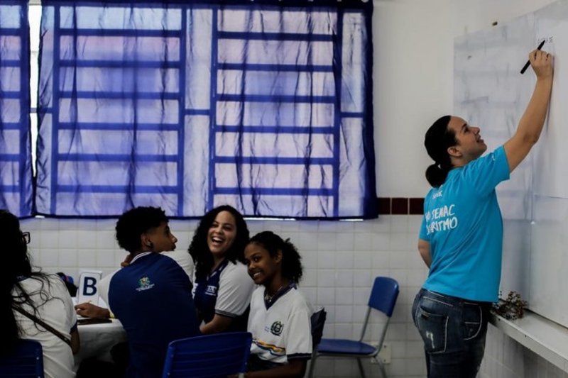 Imagem de professora e estudantes em sala de aula