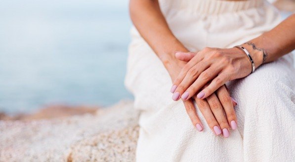 Imagem de uma mulher com esmalte nas unhas na praia