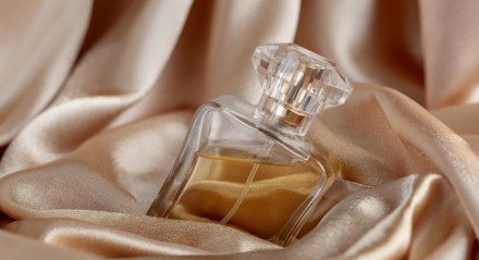 Garrafa de vidro de perfume em fundo de seda dourada


