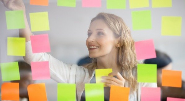 Imagem ilustrativa de uma mulher de cabelos loiros decorando um vision board
