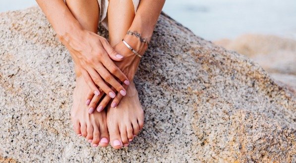 Imagem de unhas pintadas na praia.