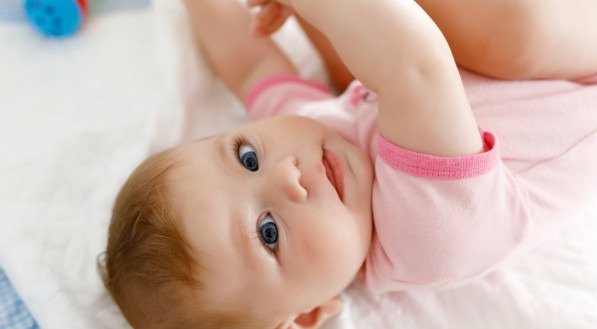 Bebê fofo tomando os pés na boca.