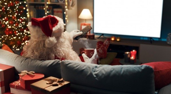Imagem ilustra pessoa vestida de Papai Noel assistindo filme