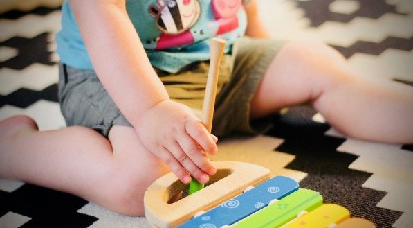 Imagem de uma criança brincando com um brinquedo musical