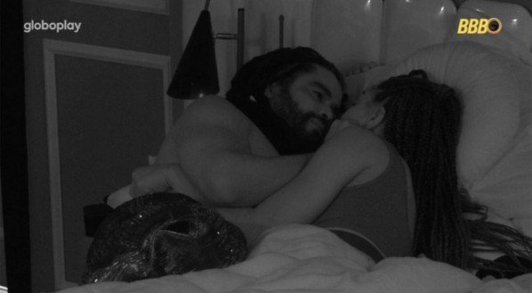 Imagem dos participantes Diogo Almeida e Alina deitados na cama no BBB 25