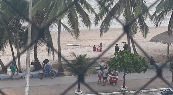 Imagem de um corpo coberto por um lençol na praia de Casa Caiada, em Olinda