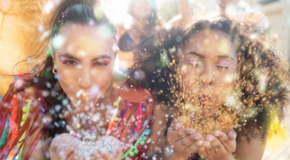 Imagem de duas amigas soprando glitter e curtindo o carnaval