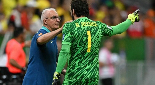 Imagem de Dorival Junior conversando com Alisson durante jogo da Seleção Brasileira