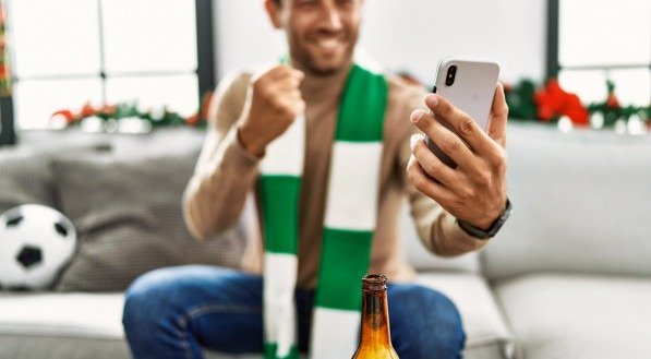 Homem assistindo futebol pelo celular