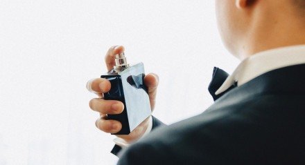 Imagem ilustrativa de um homem passando perfume