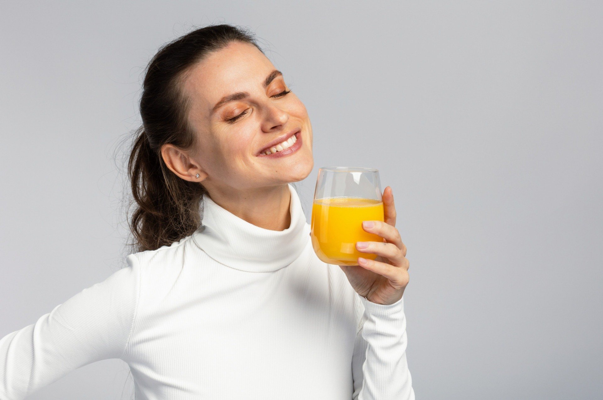 Imagem de mulher com suco de laranja na mão Tristan Ben Mahjoub/iStock