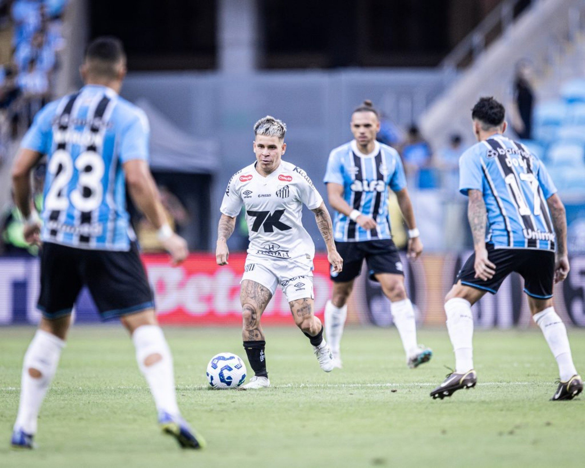 Em um duelo direto na zona de rebaixamento do Brasileirão, o Grêmio derrotou o Santos por 1 a 0 na Arena do Grêmio, com gol de Cristian Olivera. O jogo foi marcado por baixo nível técnico, com ambas as equipes apostando na velocidade dos pontas. O Santos teve mais posse de bola e criou chances, mas desperdiçou oportunidades – apenas 2 das 14 finalizações foram no alvo. Com a derrota, o time alvinegro perde pontos importantes na luta contra o rebaixamento, enquanto o Grêmio respira na tabela. Na próxima rodada, o Tricolor enfrenta o Atlético Grau pela Sul-Americana, enquanto o Santos terá uma semana para ajustes antes de encarar o Ceará.