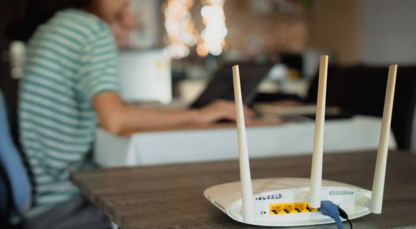 Imagem de uma mulher perto de um roteador wi-fi