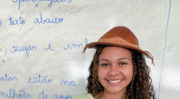 Imagem de aluna segurando caderno na sala de aula