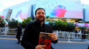Diego Medeiros segura exemplar de 'A Potência do Cinema Pernambucano' no Festival de Cannes, na Fraça