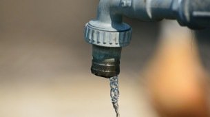 Água escorrendo de uma torneira metálica em ambiente externo