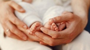Mãos adultas segurando pés de bebê
