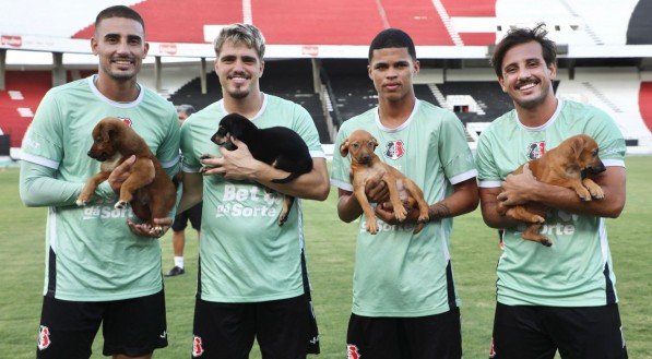 Jogadores do Santa Cruz seguram filhotes de cachorro