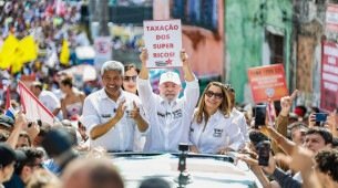 Presidente Lula segura um cartaz escrito "taxação dos super ricos" durante Caminhada do Dois de Julho, em Salvador, Bahia