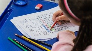 Imagem de menina fazendo atividade em sala de aula