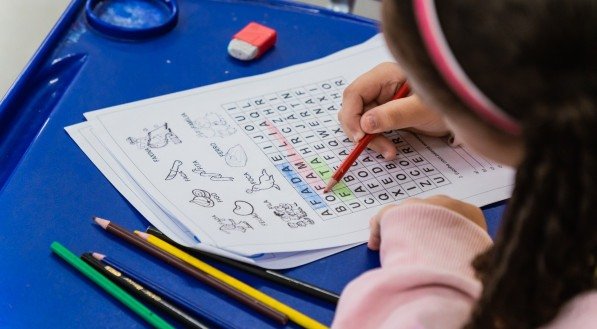 Imagem de menina fazendo atividade em sala de aula
