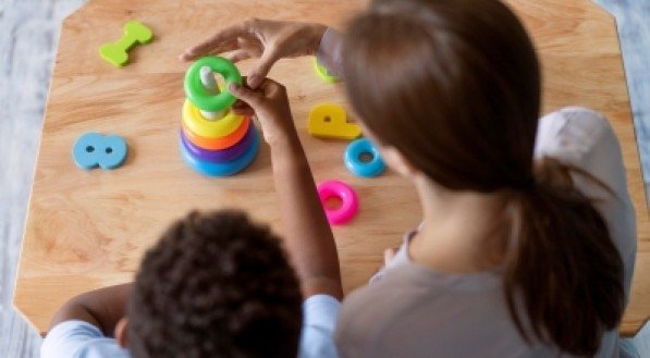Imagem ilustrativa de mulher brincando com criança, utilizando brinquedos educativos