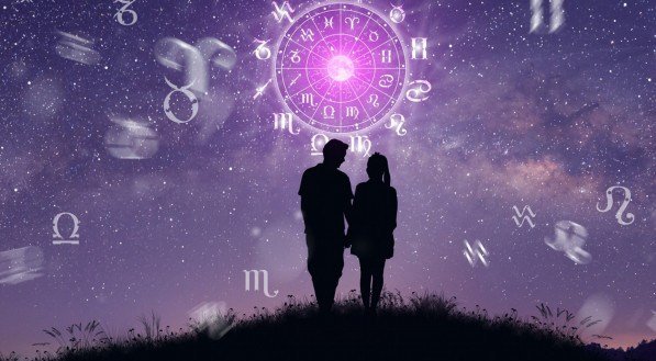 Imagem ilustrativa de um casal diante de um céu estrelado, com a roda dos signos do zodíaco acima deles