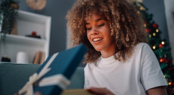 Imagem de uma jovem mulher abrindo caixa de presente