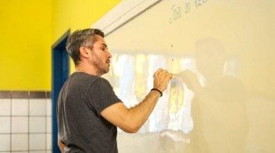 Professor escrevendo em lousa em sala de aula