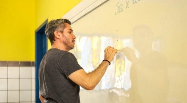 Professor escrevendo em lousa em sala de aula