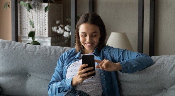 Imagem ilustrativa de uma mulher mexendo no celular!