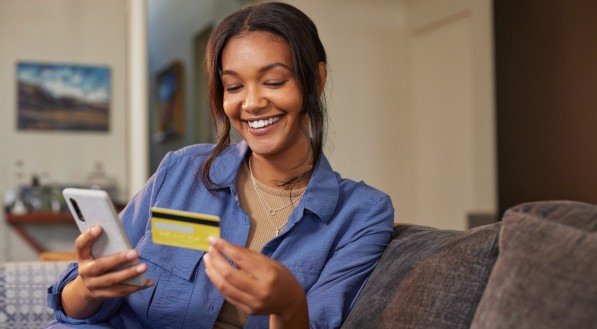 Imagem de mulher fazendo compra online com cartão de crédito e smartphone