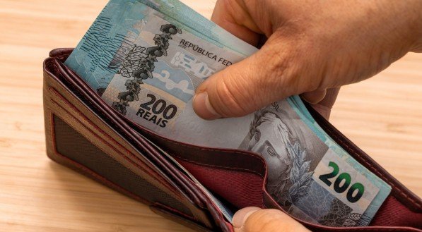 Imagem de mão tirando dinheiro da carteria