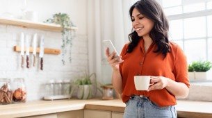 Imagem de uma mulher feliz com telefone e caneca de café