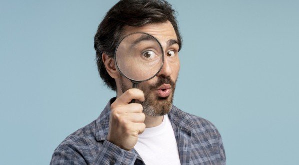 Imagem de homem curioso segurando lupa fazendo cara engraçada 