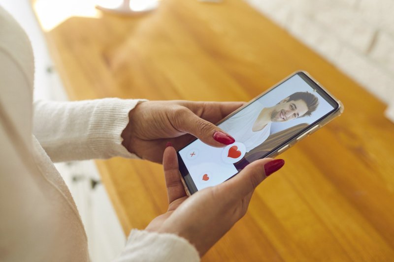 Imagem de uma mulher segurando celular em um aplicativo de relacionamento