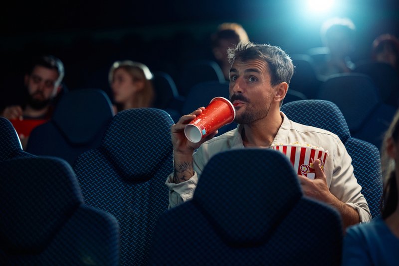 Imagem de homem sorridente curtindo em projeção de filme no cinema