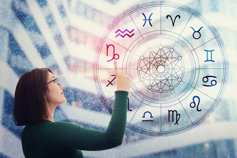 Mulher que escolhe um sinal do Zodíaco da roda astrológica para encontrar as predições futuras.