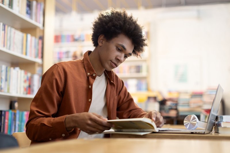 Homem na biblioteca lendo um livro
