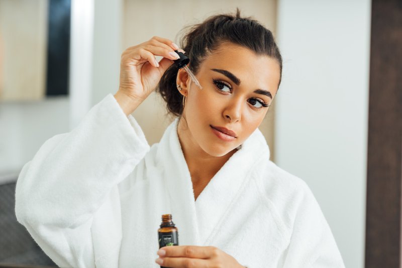 Mulher passando produto cosmético no rosto