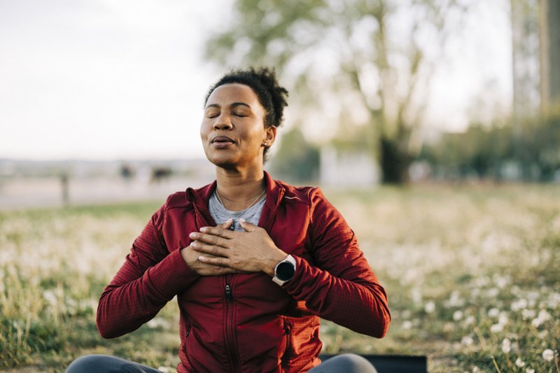 Imagem de uma mulher meditando ao ar livre